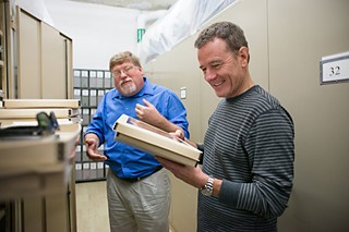 Bryan Cranston (r) looks at LBJ's eyeglasses with Michael MacDonald, LBJ Museum Registrar.