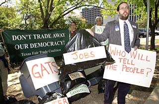Representatives from the Statewide Fair Trade Coalition convened in front of the Governor's Mansion on Monday to protest the General Agreement on Trade in Services negotiations currently under way in the World Trade Organization. Here, Bruce Banner from Education Austin, a coalition member, throws trash bags labeled Jobs, Democracy, and Environmental Services into a trash can to signify the effect that GATS-required privatization may have on local and state governments. The coalition says that these local and state governments are being kept out of the loop in GATS negotiations.