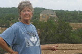 Lick Creek resident Pepper Morris serves as a volunteer water quality monitor for the LCRA and notified the agency that the creek was showing evidence of degradation. Behind her is the model home for West Cypress Hills.