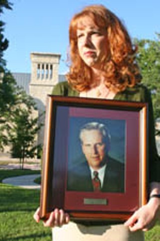 Lari Burson holding a portrait of her late father, Mike Burson