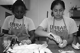 Kayla Washington and Veronica Garcia cutting cucumbers at Caritas