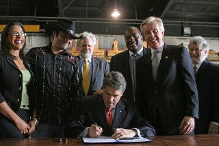 Gov. Rick Perry (center), flanked by Rep. Dukes (far left), Robert Rodriguez (left), and other supporters of Texas film, signs HB 873.