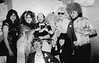 Mardi Gras '77 backstage at Armadillo World Headquarters after the Fools show. Top row  (l-r): host and emcee Micael Priest; Big Rikke, the irrepressible Guacamole Queen; Van Wilks, Guitar God and leader of the Fools; Spook, the Armadillo Rock & Roll Cat; Margaret and Stephen Moser, the Nurses From Outer Space; Big Boy Medlin, sports editor for the <i>Austin Sun</i> and founder of E! the Entertainment Network. Bottom Row (l-r): Marty  Manning, KOKE-FM  morning man and TV bingo host; Janet Burris, Sheauxnough Studios business manager.
<p>(Courtesy Stephen Macmillan Moser)
