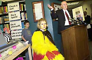 Becky Marek, sitting next to Mayor Gus Garcia, is an administrative assistant at the Hampton branch who agreed to dress up as a chicken to promote the branch's Chick It Out campaign, designed to publicize the new computerized system at the Hampton branch that allows patrons to check out their own library books.