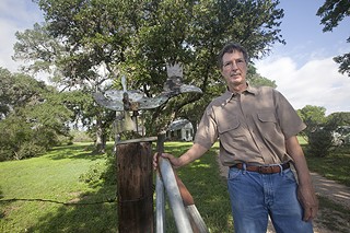 Michael Adams, director of the Dobie Paisano Fellowship Program, next to the gravel driveway leading to the ranch house and the iconic, sculptured wood roadrunner that greets ranch visitors.