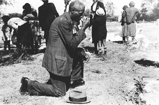 Negro crossing himself and praying over grave of relative in cemetery, All Saints' Day, New Roads, La., November 1938