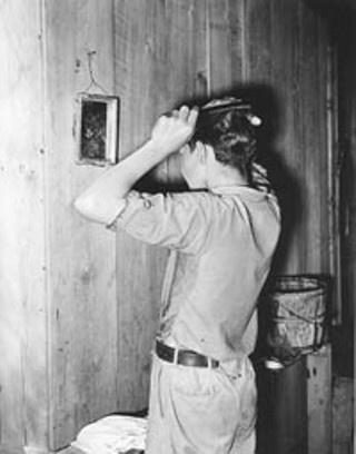 Migrant boy combing his hair at his home near Muskogee, Okla., July 1939