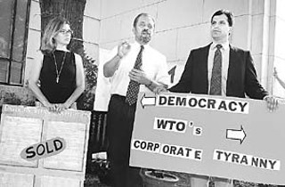The Fair Trade Coalition's Leslie Ramsey, Texas Civil Rights Project lawyer Jim Harrington, and Austin City Council Member Raul Alvarez protested in front of City Hall on Sept. 10 against the World Trade Organization's ministerial meeting held last week in Cancýun, Mexico. Mocking the effect they predict WTO policies will have on people, activists awarded booby prizes to hardworking Americans: giant pink slips, $5-per-gallon water, Enron's new U.S. constitution (held here by Ramsey), dirty air, and polluted food. The Cancýun talks collapsed on Sunday, to the chagrin of the U.S. trade delegation and the delight of many small, Third World farmers.