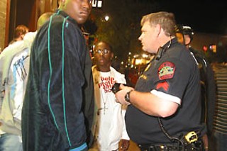 A Sixth Street cop checks the IDs of club patrons.