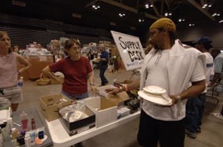 A Katrina evacuee scans tables for needed living supplies as
he tries to assemble a life at the Austin Convention Center.