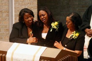 Anyce Joe Chanel Obey, supported by family members, 
mourns her mother.