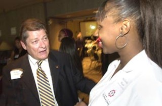 American YouthWorks director Richard Halpin (l) talks with recent graduate Melinda Shaw at a luncheon last week. Shaw credits AYW's charter school with helping turn her life around; AISD is considering entering into a partnership with the organization.