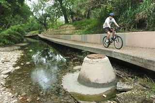 Shoal Creek Downtown: Better lighting and other improvements would make the Shoal Creek Greenbelt Trail a safer, more inviting, and well-used Downtown walk-to-work and strolling route. Also high on the wish list: completing the trail between Fifth Street and West Avenue. PARD needs to acquire easements from landowners to close the gap and permanently locate the trail above the creek. Creek banks need stabilization work, too, near both Fifth and 15th streets.
<p>
Waller Creek: The new $123.6 million Waller Creek Tunnel project offers an exciting opportunity to turn the blighted Waller Creek Trail into a beautiful Downtown amenity. But funds for trail improvements were not included in the tunnel project; parkland-dedication-fee revenues could fill the gap, as the tunnel opens up more than a million square feet of Downtown land for redevelopment. Council Member Sheryl Cole hopes the fee can help improve the Waller Creek Trail from Waterloo Park to Town Lake, bringing together more than 21 miles of Downtown trails.