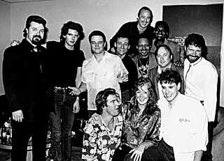 Back row: Kim Wilson, Robert Cray. Middle row: Omar Dykes, Charlie Sexton, Jimmie Vaughan, Fran Christina, Art Neville, Stephen Stills, Chuck Leavell. Front row: Dennis Quaid, Bonnie Raitt, Preston Hubbard.