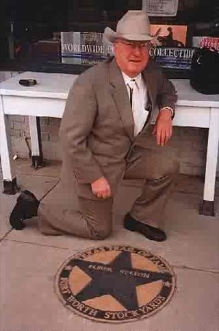 Elmer Kelton kneeling beside his star at the Fort Worth Stockyards