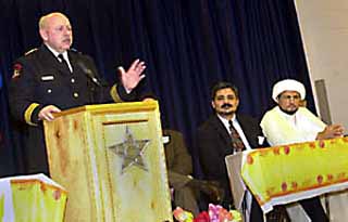 APD Chief of Police Stan Knee speaks at Eid-Ul-Fitr, a celebration for the end of Ramadan, which was hosted by the Islamic Ahlul Bayt Association of Austin at Dennis Cowan Elementary School Sunday evening. In attendance were clergymen from the Islamic, Christian, and Jewish faiths. Seated next to Knee are (l-r) Abdullah Yassine and Sheikh Safdar Razi.