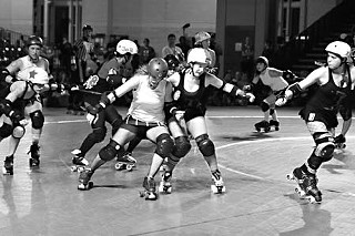 Lucille Brawl (center) blocks while Olivia Shootin’ John (left) takes a skirt-whip off Rice Rocket (3e8) as the Texas Rollergirls’ travel team, the Texecutioners, faces the Oly Rollers at the WFTDA 2009 finals in Philadelphia.