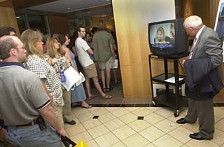 Citizens watch the City Council meeting while waiting in line to be admitted to the Stratus hearing.